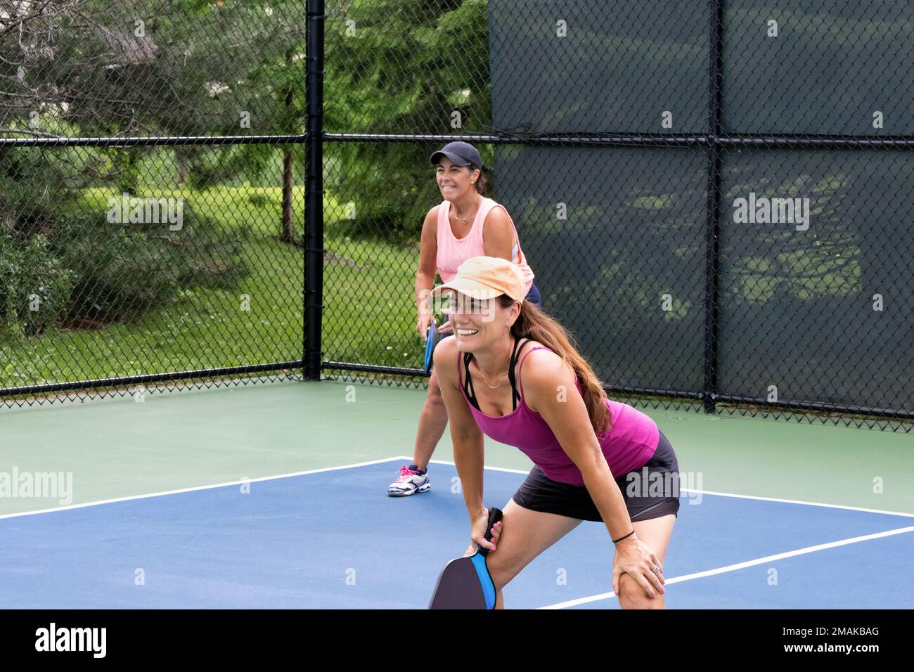 Two smiling pickleball players prepare for action on a suburban