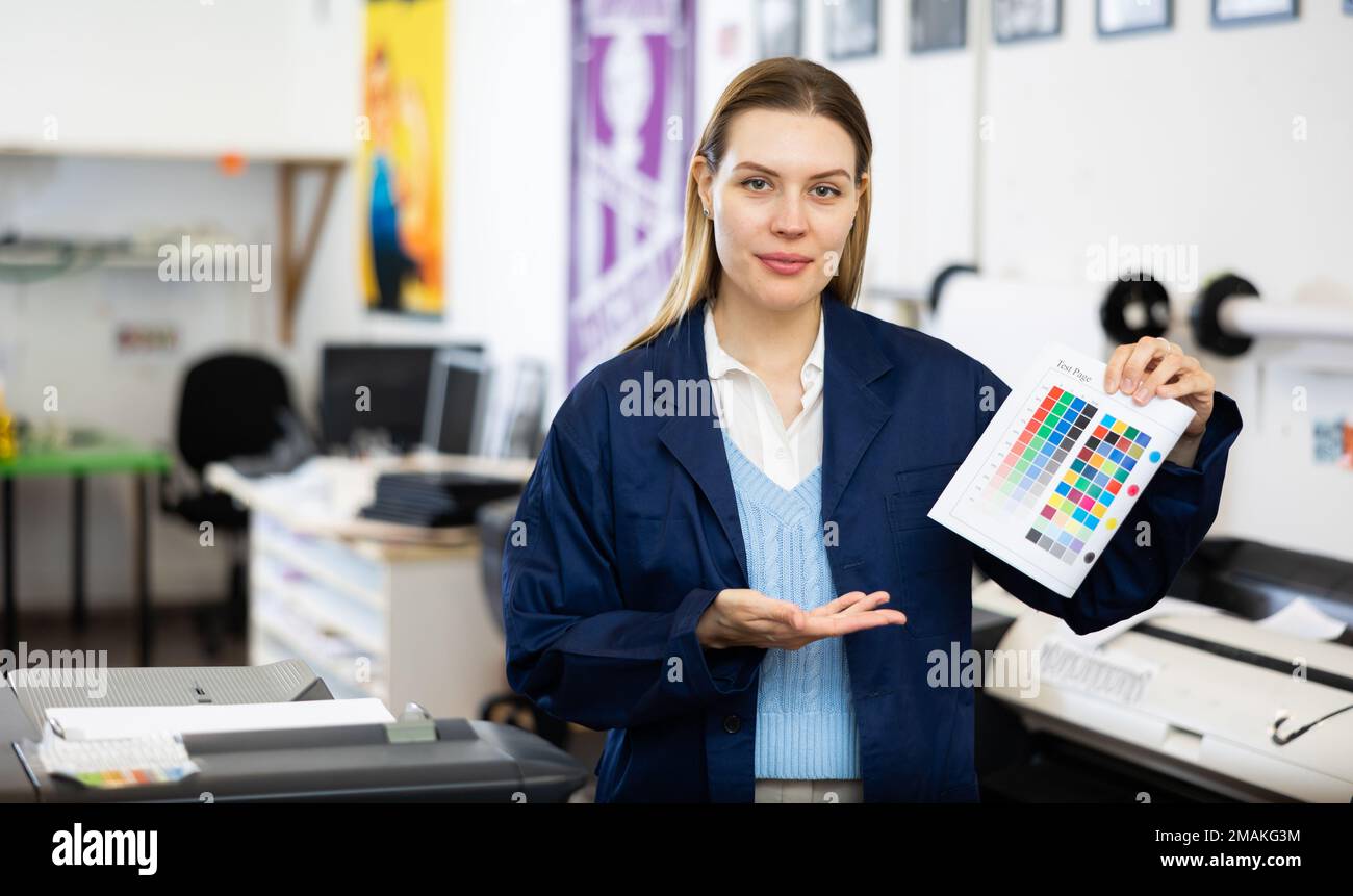 Portrait of positive woman printing office worker with colour test page Stock Photo