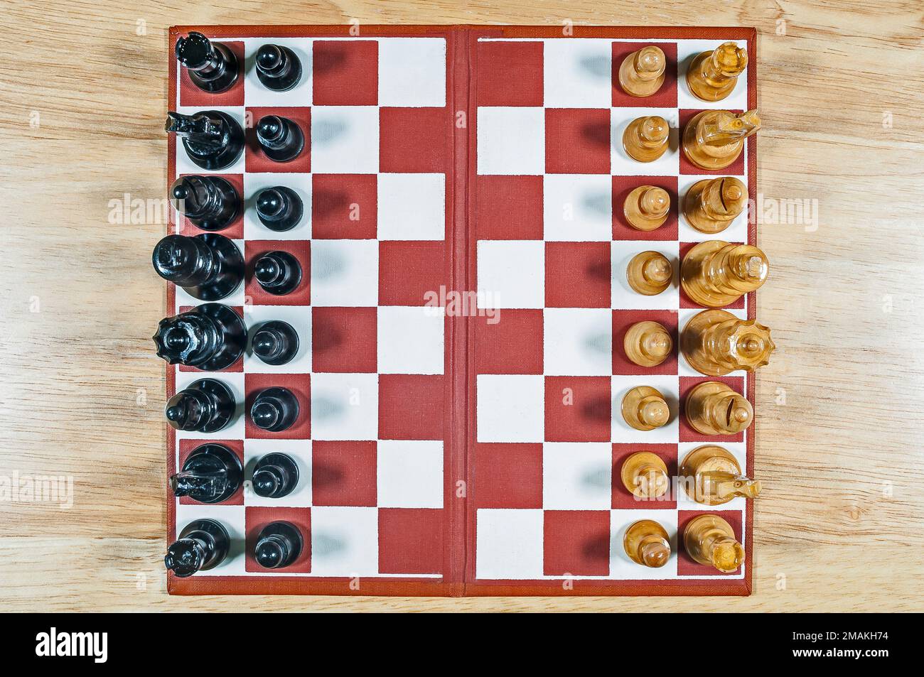 Overhead view of small wooden vintage chess set and board on a wood table.  Image may be rotated as desired for placement. Stock Photo