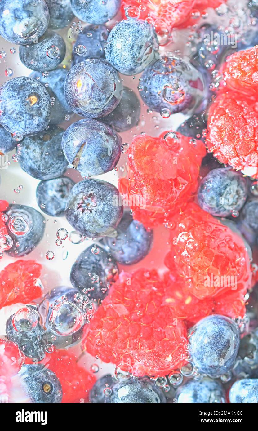 Blueberries and raspberries in liquid with bubbles. Colourful ripe