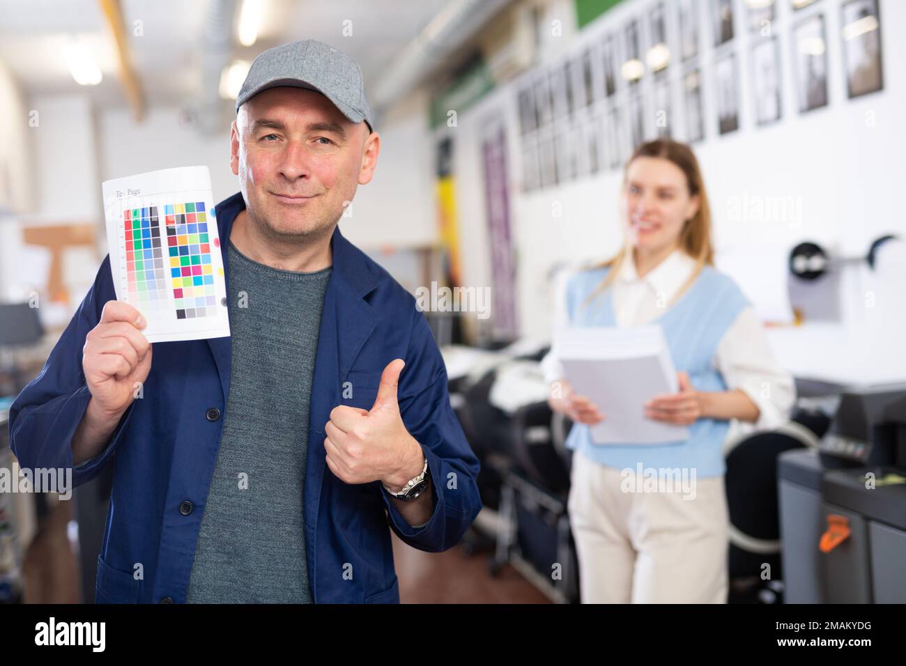 Service engineer demonstrating test page with color palette in his hand ...