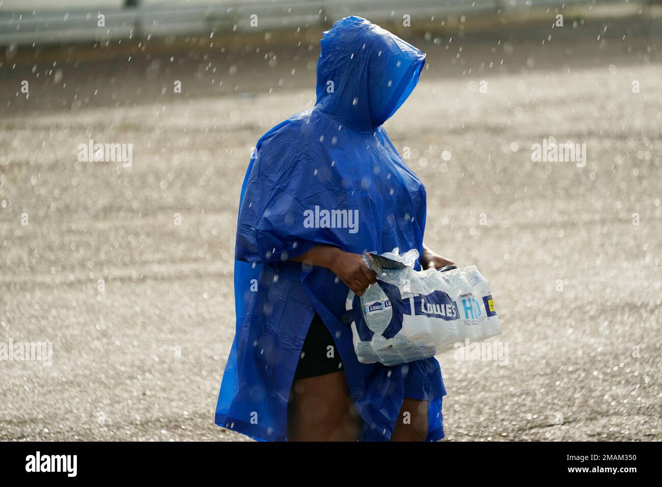 A volunteer carries a case of water in the rain as a coalition of