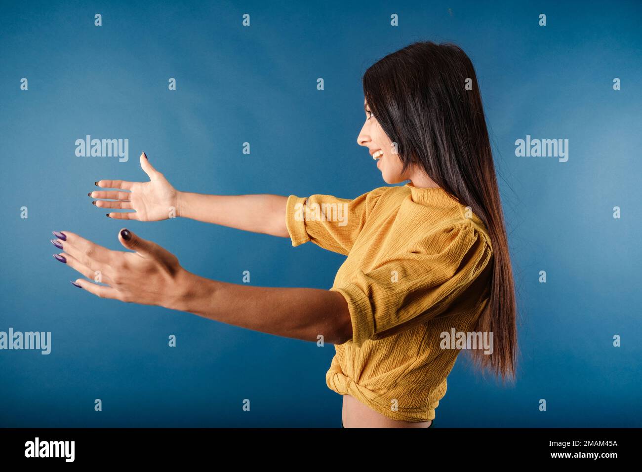 Side view of cheerful woman isolated over blue background outstretching hands as if giving for free, offering to embrace, complacency and egoism conce Stock Photo