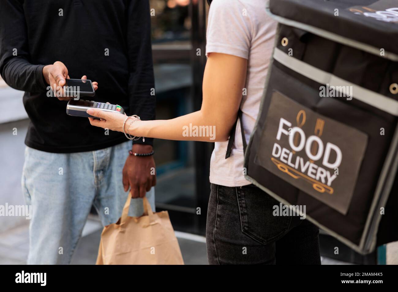 Client making contactless mobile payment for food delivery closeup, nfc technology. Courier hand