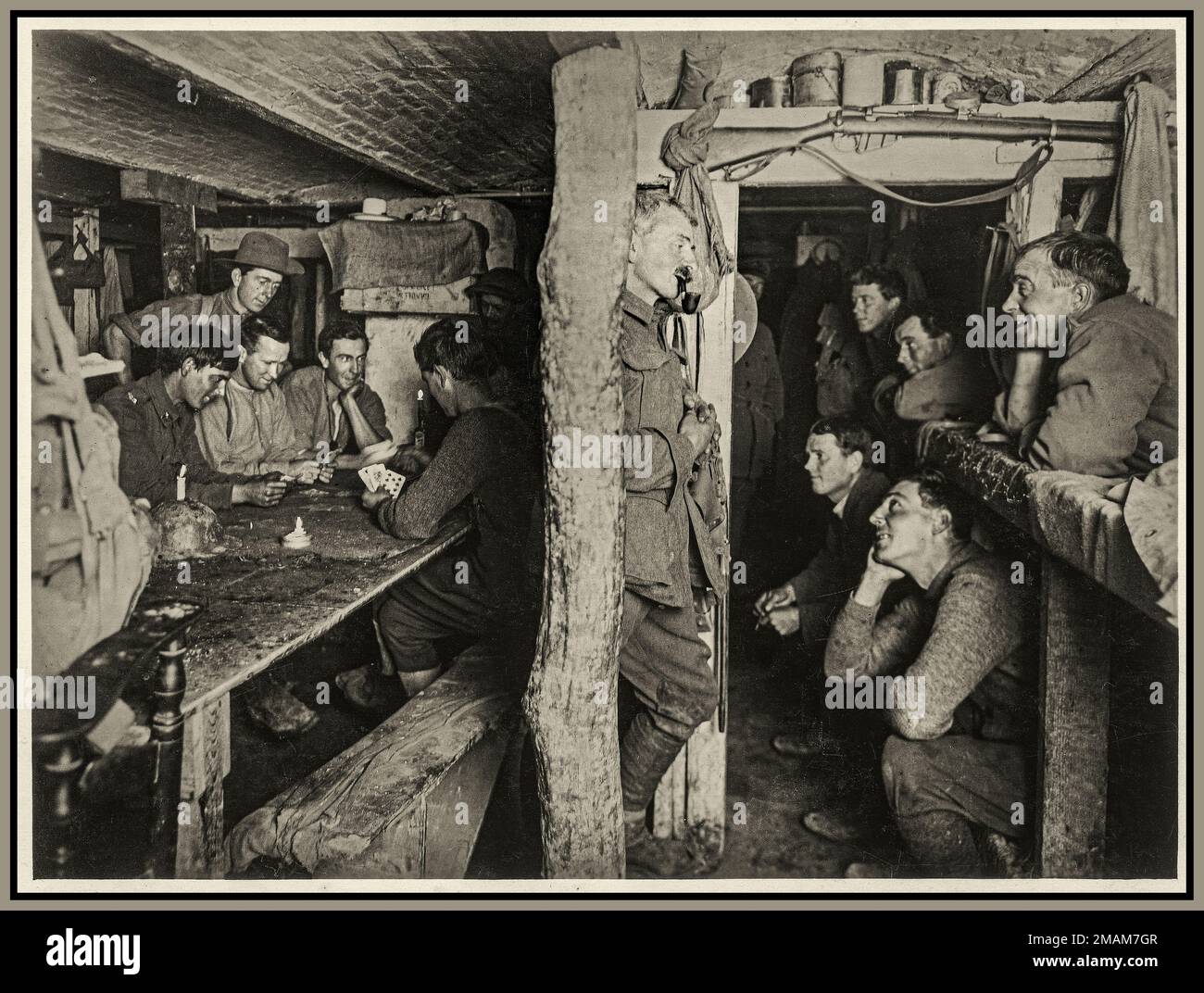 WW1 1915 Propaganda image 'Safe from the shells' - Canadian soldiers playing cards in dug-out shelter in the trenches (probably The Somme), at The Front in France during World War 1 Stock Photo