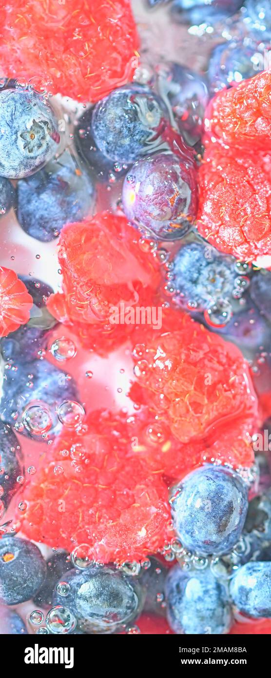 Blueberries and raspberries in liquid with bubbles. Colourful ripe