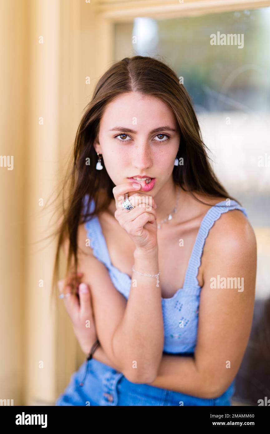 Teenage Girl Sitting and Biting Lip Turning to Face Camera Stock Photo