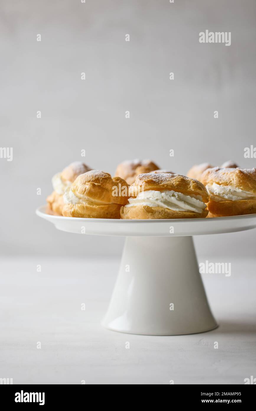 plate of cream puffs decorated with powdered sugar on light grey ...
