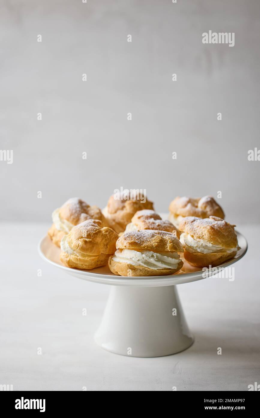 plate of cream puffs decorated with powdered sugar on light grey background Stock Photo