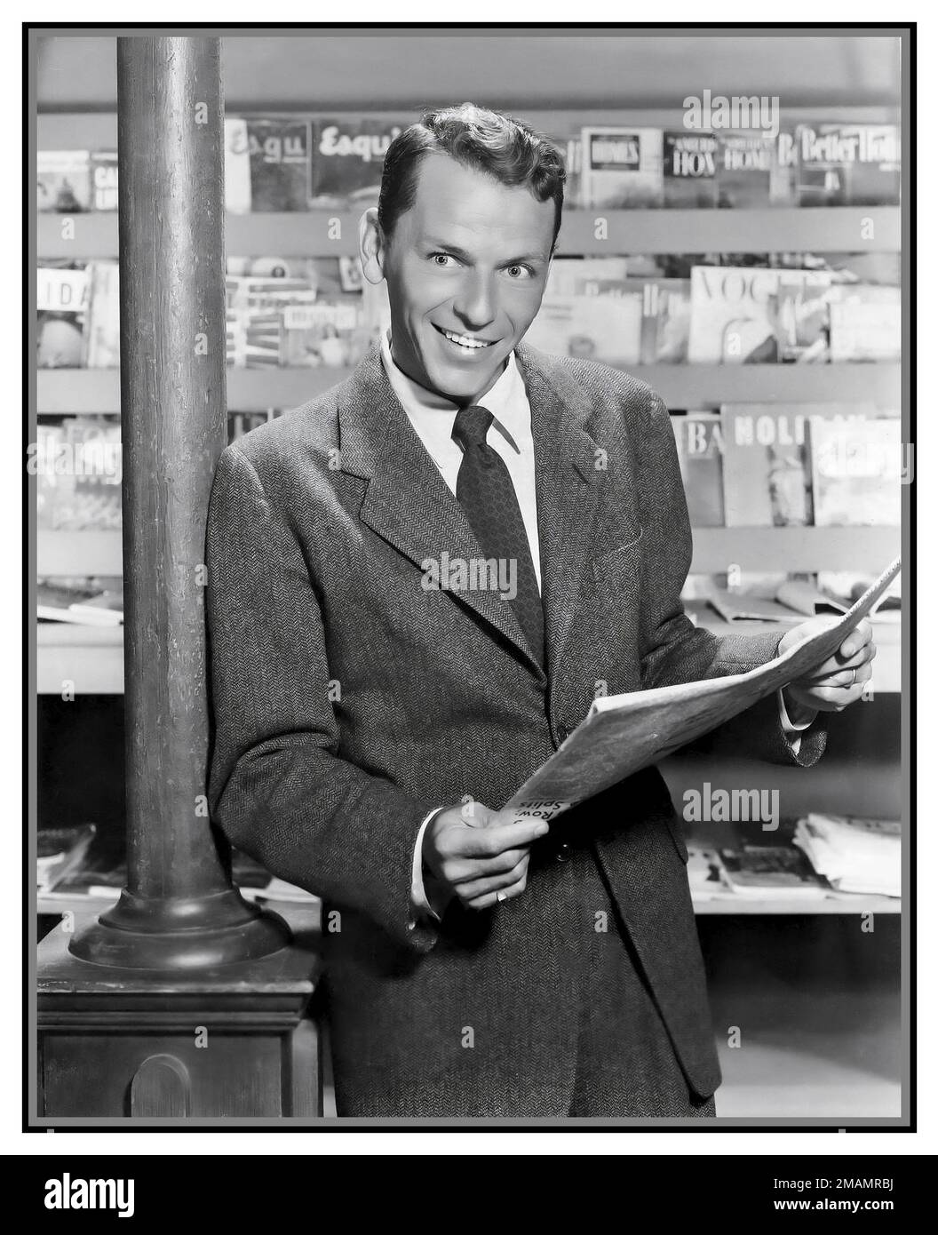 FRANK SINATRA HOLLYWOOD PUBLICITY POSED STUDIO STILL Publicity photo of Frank Sinatra in 1954 holding a newspaper.in magazine newspaper store shop outlet Stock Photo