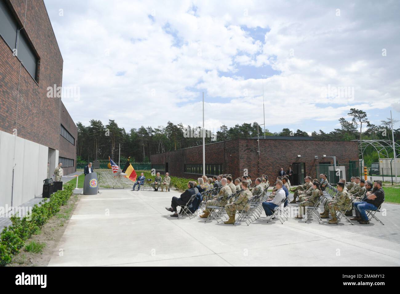 Assembled guests sit outside the brand new 701st Munitions Support Squadron mission operation center celebrating 60th anniversary of USAF support of NATO at Kleine Brogel Air Base, Belgium, May 31, 2022. The mission operation center is expected to enhance the MUNSS ability to support the Dual Capable Aircraft mission through consolidated capabilities and upgraded 21st century technology. Stock Photo