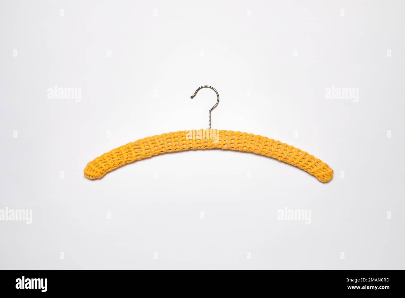 Recycled yellow hanger covered with crochet work. Crocheted shell stitch cloth hanger cover. Slow fashion, circular economy, retro style, renew DIY ho Stock Photo