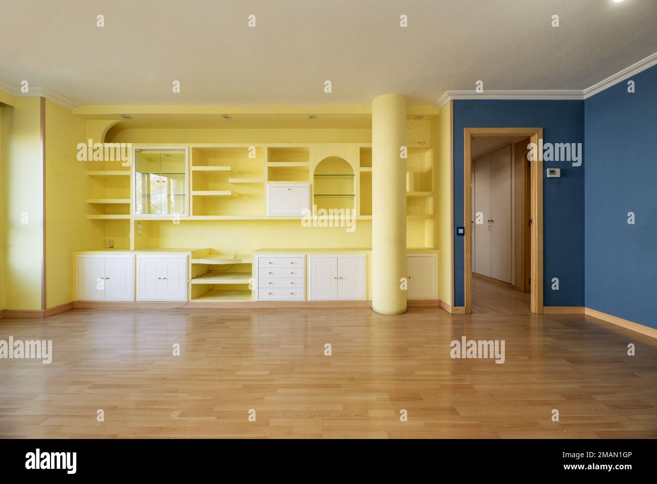 Living room of an empty house with yellow painted plaster work furniture and another blue wall and plaster molding on the ceiling Stock Photo