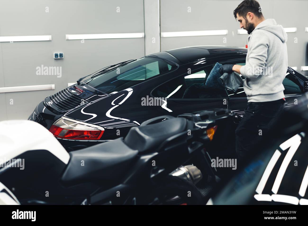 Ceramic paint protection. Man during car detailing. Process of applying ceramic coating onto black sports car with a microfiber cloth. High quality photo Stock Photo