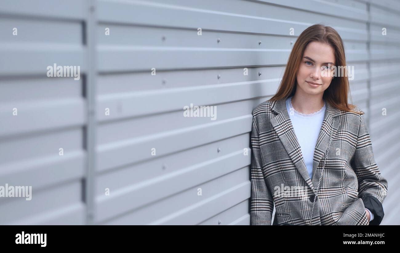 Portrait of a young girl in a blazer by a wall on the street. Stock Photo