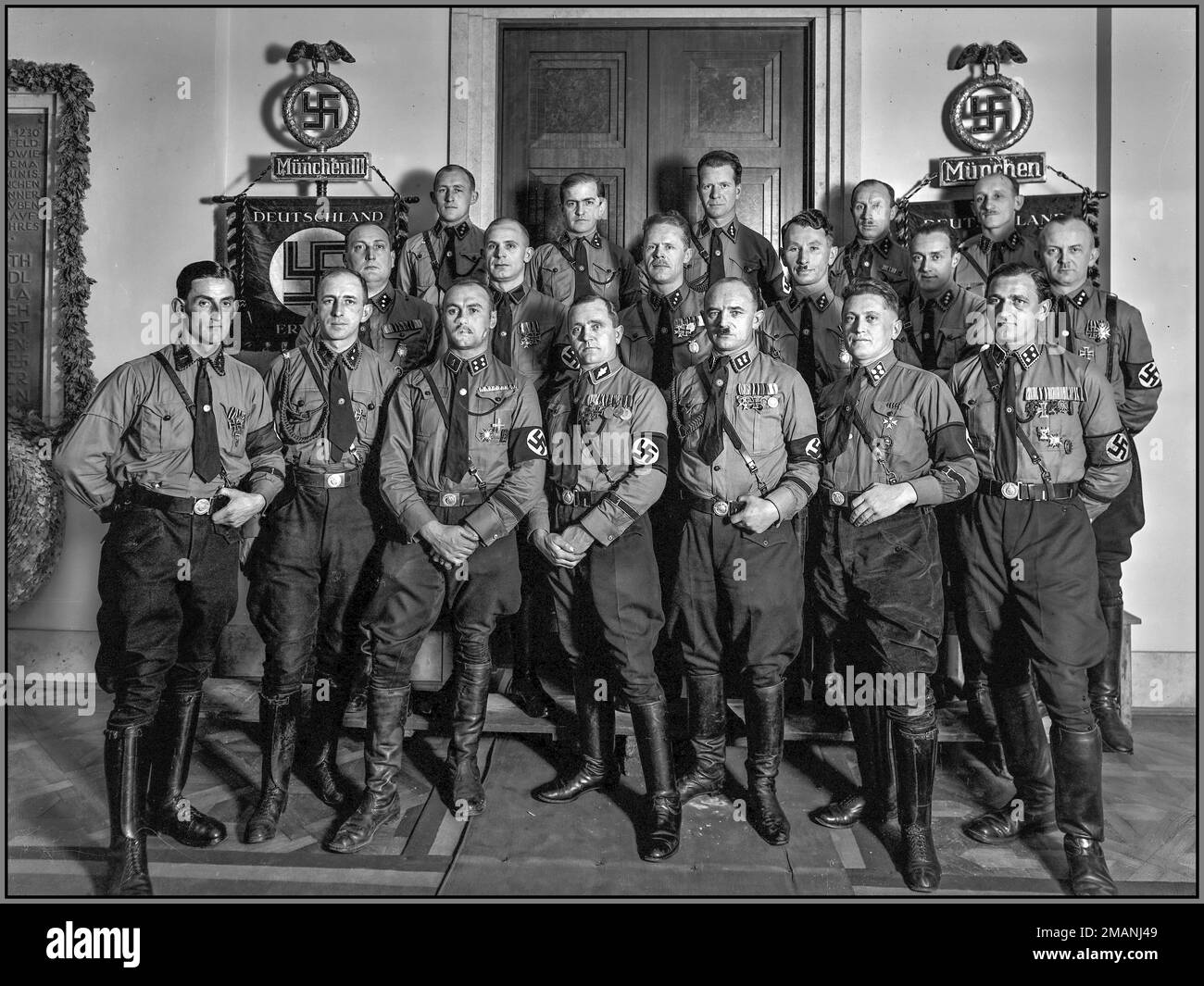 Nazi Propaganda group photo of uniformed leaders (German: SS Führer) of the SS Regiment Die Schutzstaffel der NSDAP (SS) Munich, in front of the Senatorensaal (Senators' Hall, conference/council room) by the Ehrentafeln/Heldentafeln, honour plaques/heroes tables of the Blutzeuge, the November 9th 1923 Putsch Nazi martyrs, in the lobby of the Brown House in Munich, Germany, ca. 1931–1932. The 1st SS-Standarte was a regimental command of the Allgemeine-SS and one of the units in the General-SS order of battle. Based in Munich, the 1st SS Standarte was charged with protection of top Nazi leaders Stock Photo