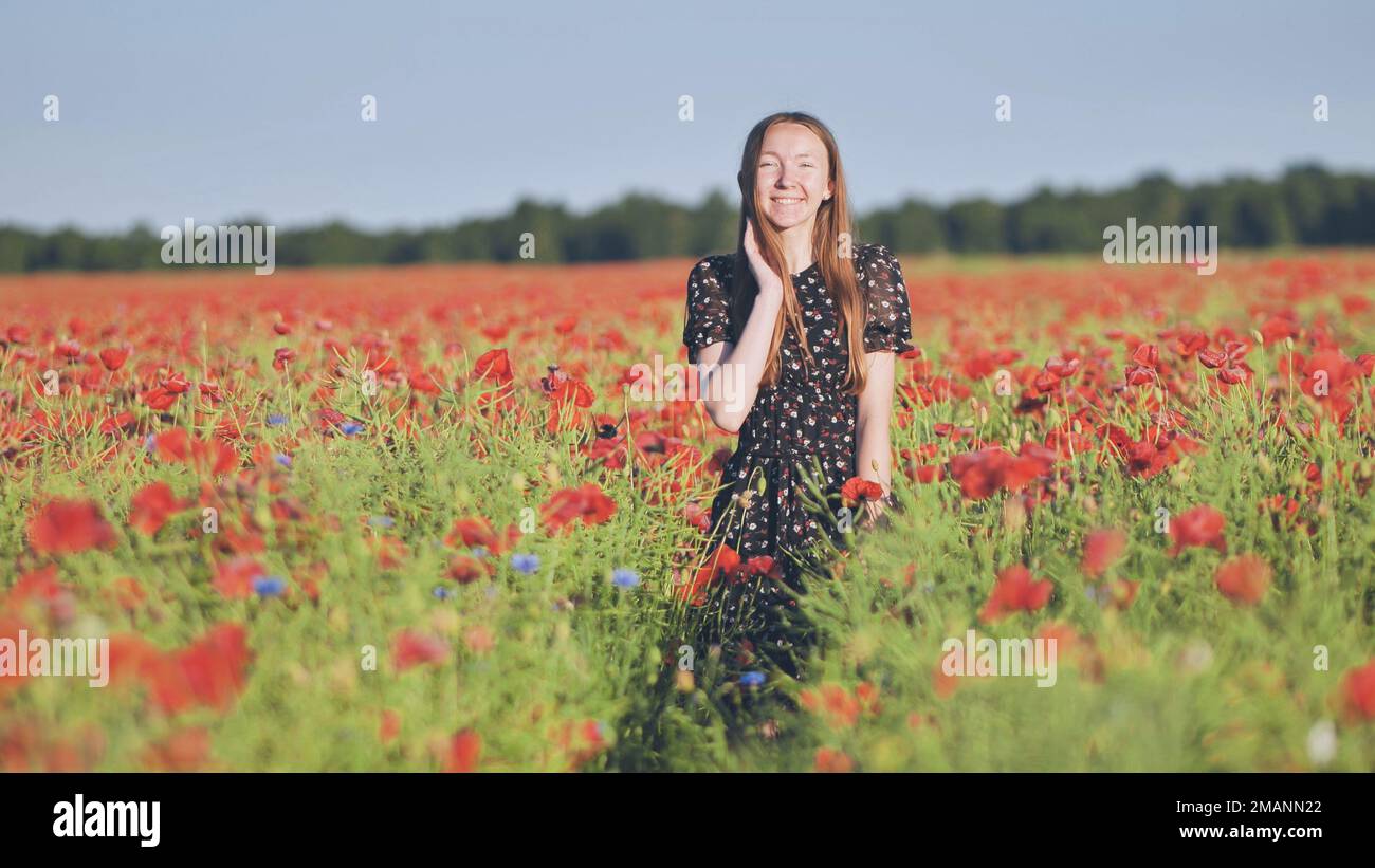A young girl walks through a red poppy field Stock Photo - Alamy