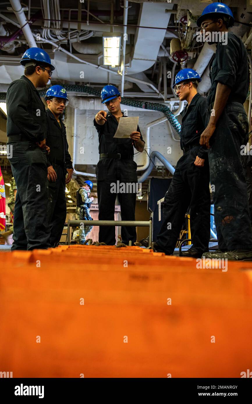 SASEBO, Japan (June 1, 2022) Sailors assigned to the forward-deployed amphibious assault ship USS America (LHA 6) perform routine maintenance on a pilot ladder in the ship’s vehicle stowage area. America, lead ship of the America Amphibious Ready Group, is operating in the U.S. 7th Fleet area of responsibility to enhance interoperability with allies and partners and serve as a ready response force to defend peace and stability in the Indo-Pacific region. Stock Photo