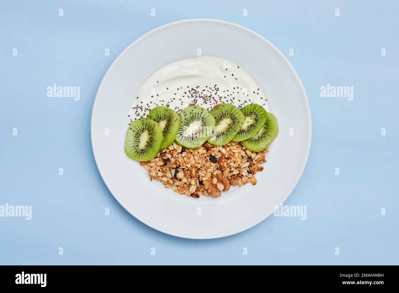 some fruit and nuts on a white plate with yorame in the middle, topped with grano de galloas Stock Photo