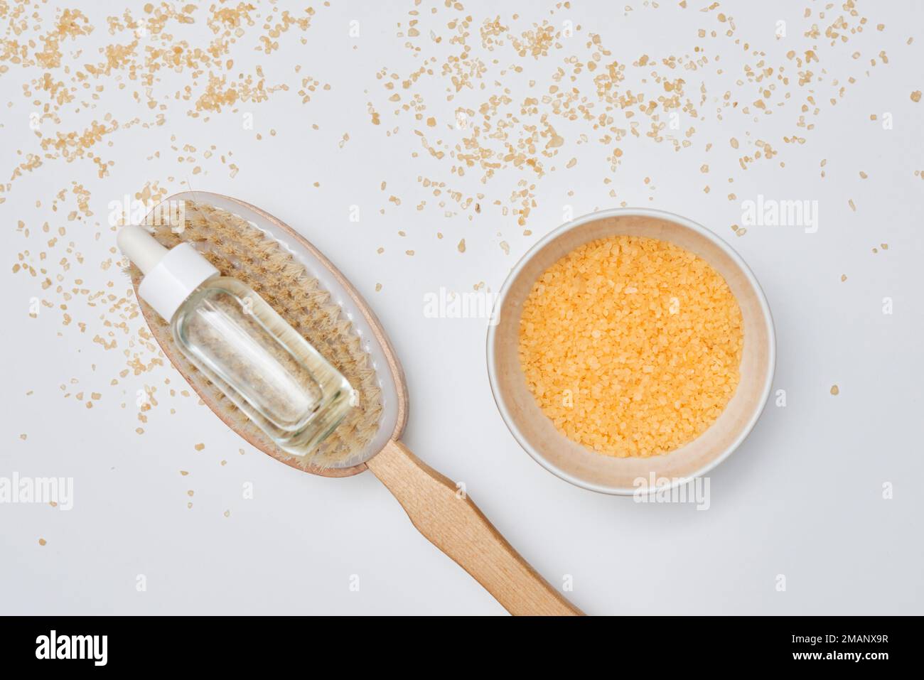 a wooden spoon with some sugar on it next to a small bowl filled with oats and gold flakes Stock Photo