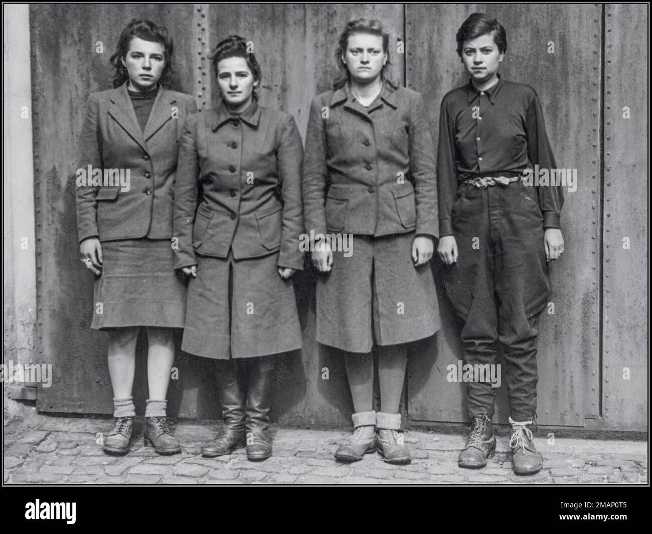 BELSEN FEMALE GUARDS Marta Löbelt telephone operator, Gertrud Rheinhold, Irene Haschke and Anneliese Kohlmann shortly after their arrest at Bergen Belsen, 02 May 1945. The first three are wearing their Nazi uniform while Kohlmann is wearing poorly fitted men's uniform because when arrested she was wearing prisoner uniform trying to disguise herself as a Jewish woman. Date 2 May 1945 Stock Photo
