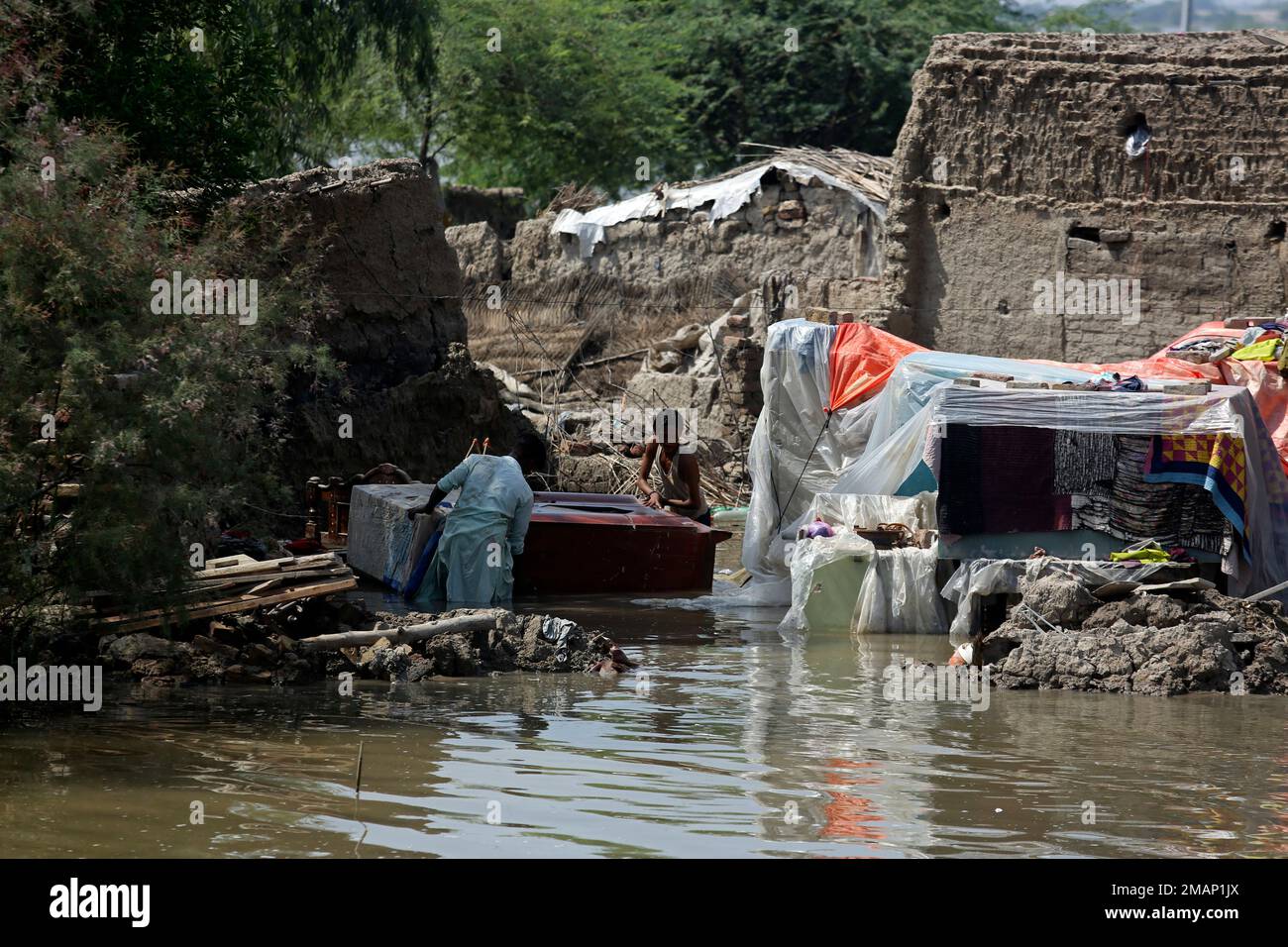 Men carry usable belongings salvaged from their flood-hit home across a ...