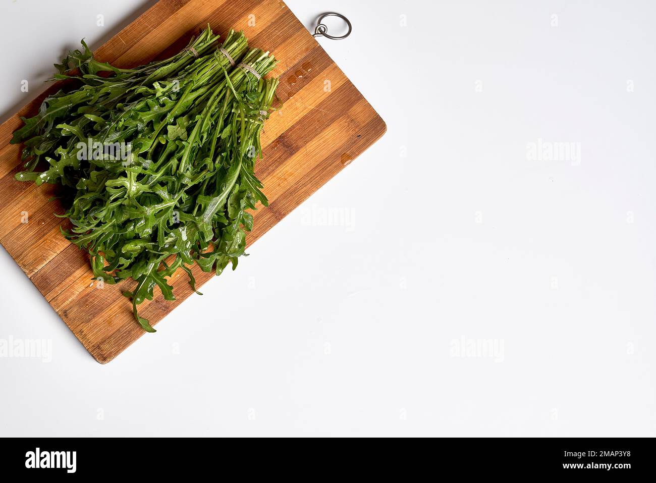 some green vegetables on a wooden cutting board with a knife in the middle and a white background to the right Stock Photo