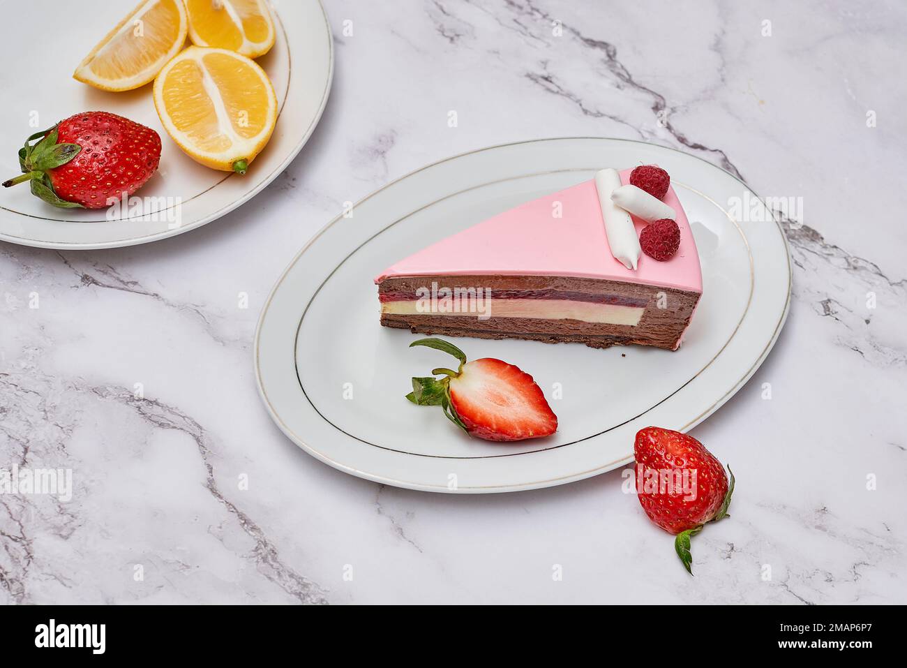 two slices of cake with strawberries and lemons on the plate next to each one slice is half eaten Stock Photo