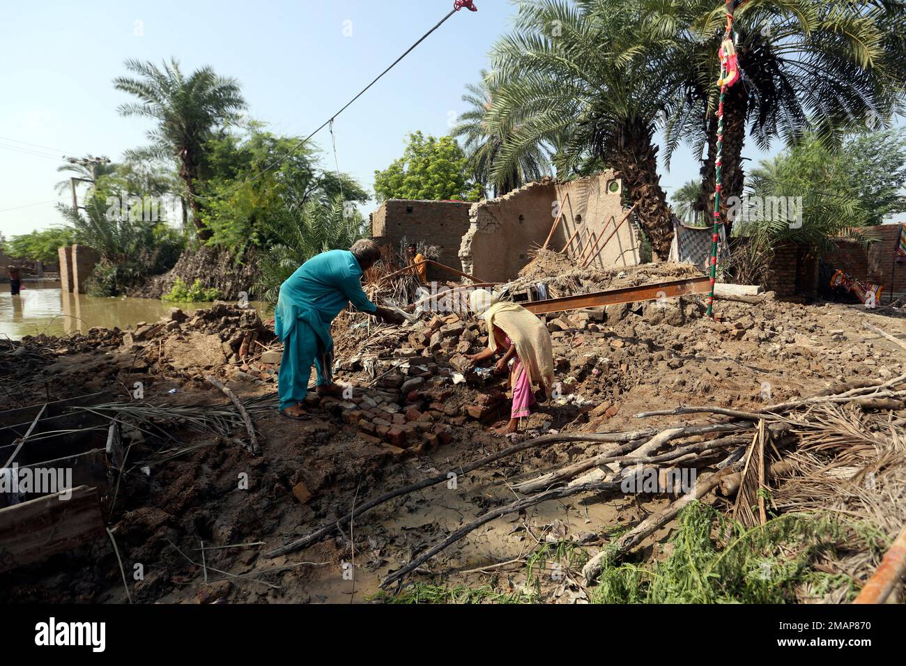 A family collects items from the remains of their home damaged by ...