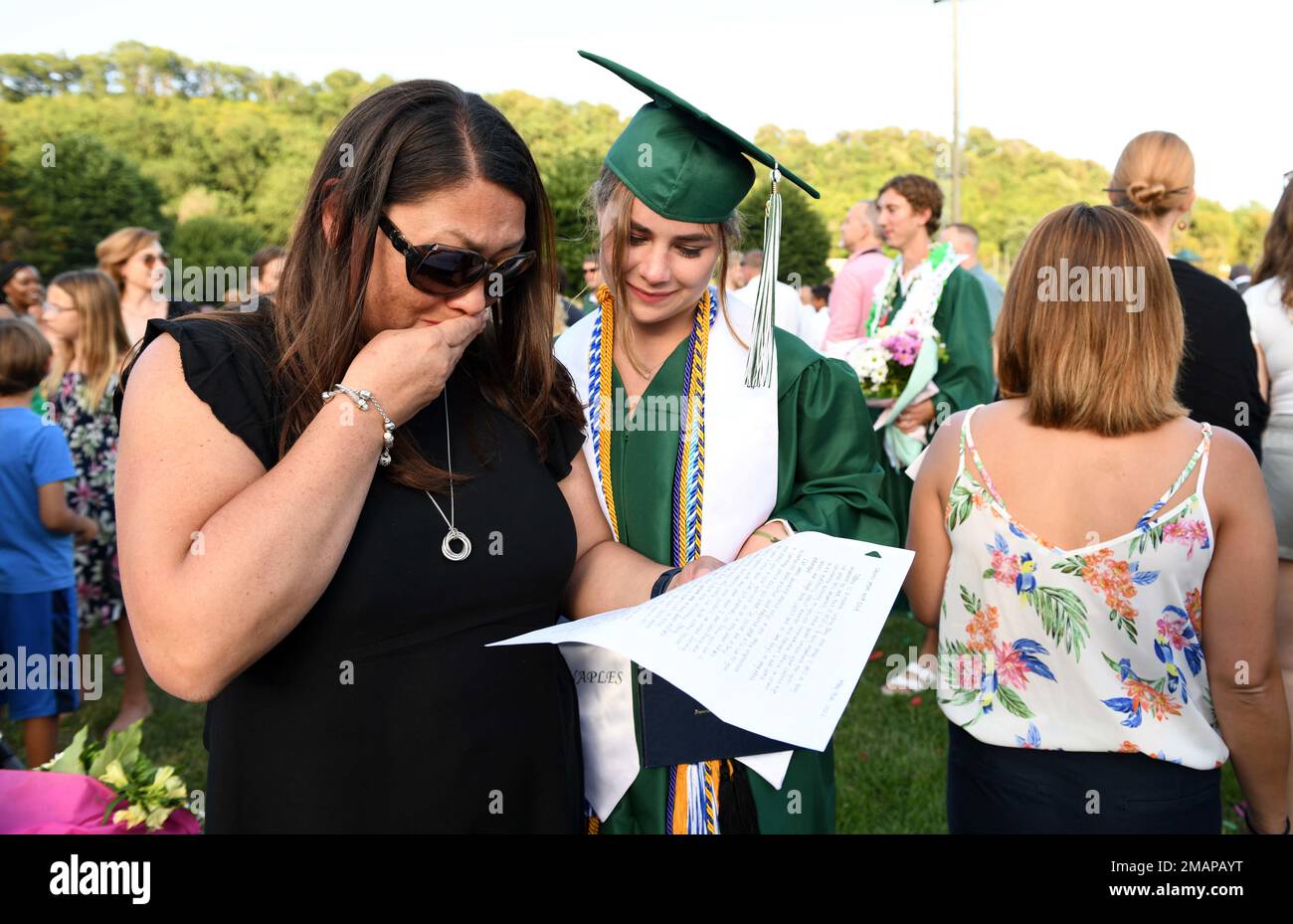220602-N-IE405-2177 POZZUOLI, Italy (June 2, 2022) Jennifer Stewart, left, reads an appreciation letter from her daughter Sydney Stewart during the Class of 2022 graduation ceremony at U.S. Naval Support Activity (NSA) Naples' Carney Park in Pozzuoli, Italy, June 2, 2022. NSA Naples is an operational ashore base that enables U.S., allied, and partner nation forces to be where they are needed, when they are needed to ensure security and stability in the European, African, and Central Command areas of responsibility. Stock Photo