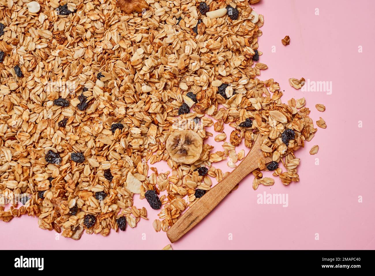 oats on a pink surface with a wooden spoon in the background and an image of blueberries, almonds, and nuts Stock Photo