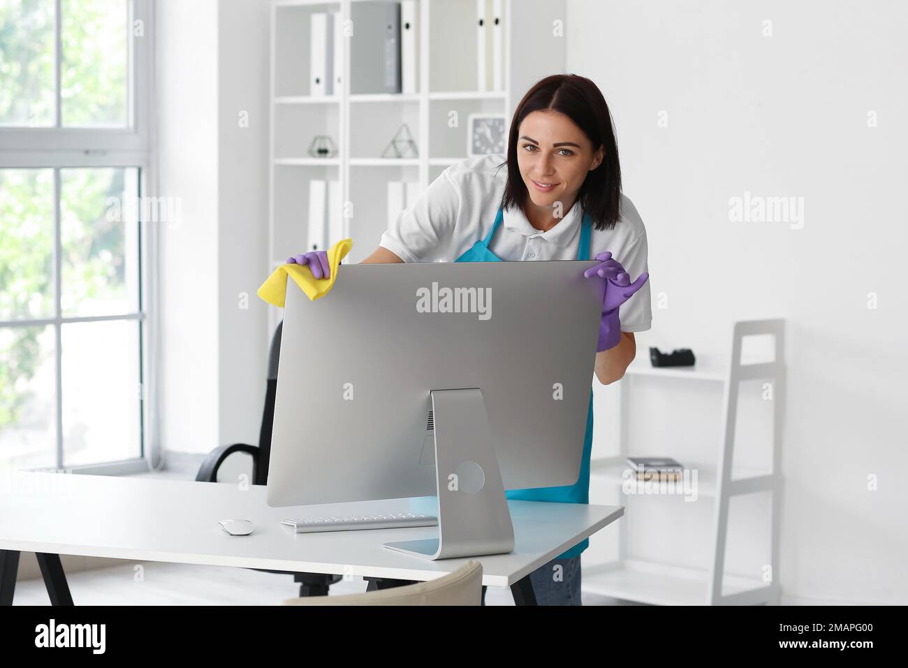 Female janitor wiping computer in office Stock Photo - Alamy