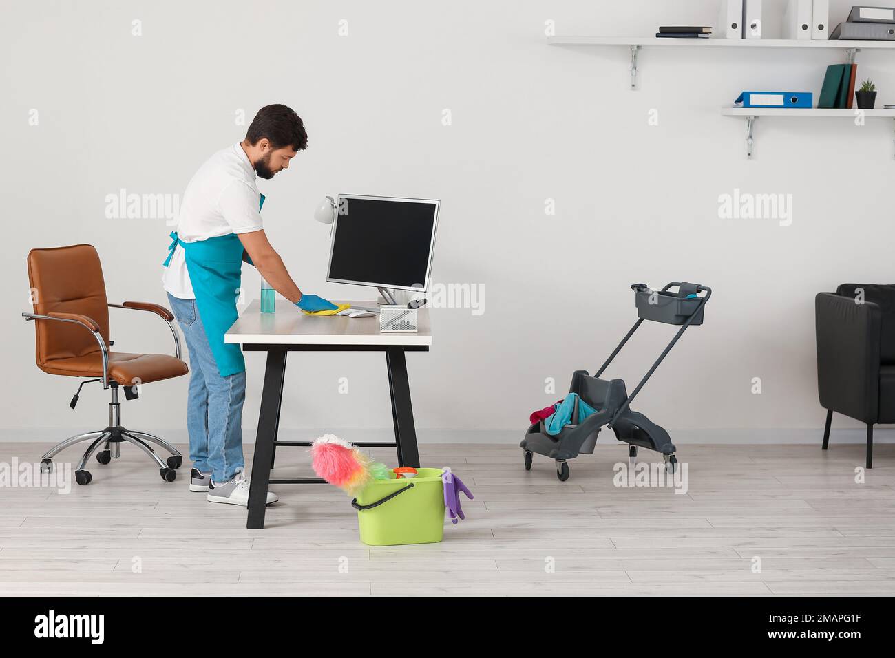 Male janitor cleaning desk in office Stock Photo Alamy