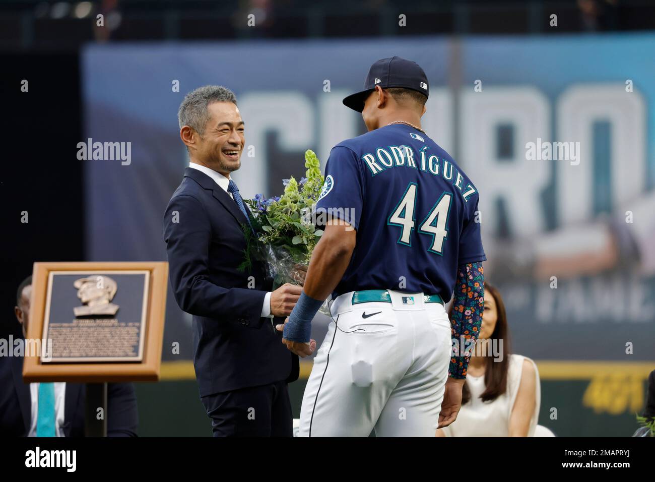 Former Seattle Mariners player Ichiro Suzuki, left, is presented with a  bouquet of flowers by Mariners' Julio Rodriguez as he is inducted into the Mariners  Hall of Fame during a ceremony before
