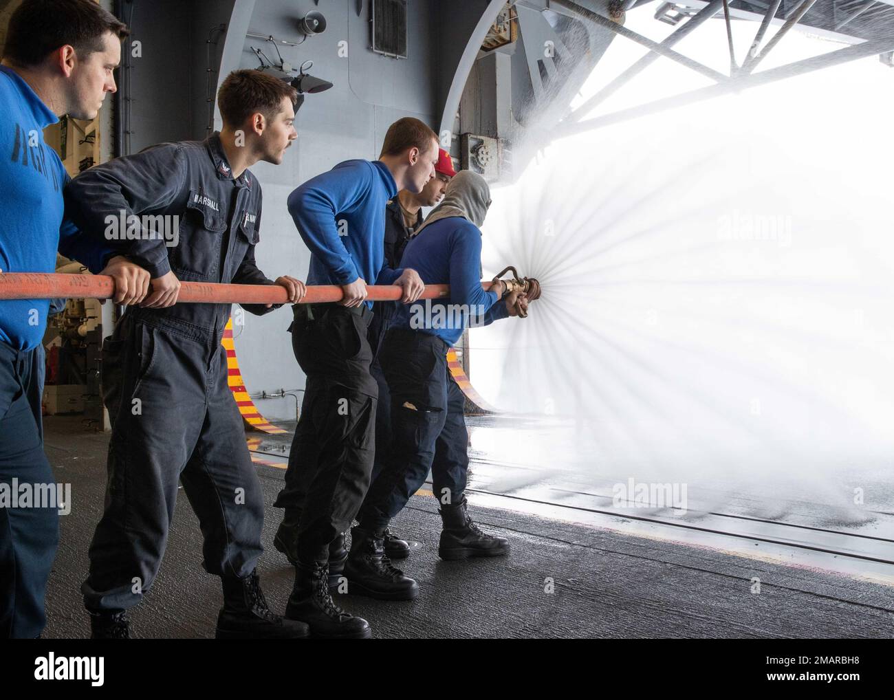 220604-N-TT639-1025 PACIFIC OCEAN (June 4, 2022) – Sailors practice fire hose handling during a general quarters drill in the hangar bay aboard amphibious assault carrier USS Tripoli (LHA 7), June 4, 2022. Tripoli is underway conducting routine operations in U.S. 7th Fleet. Stock Photo