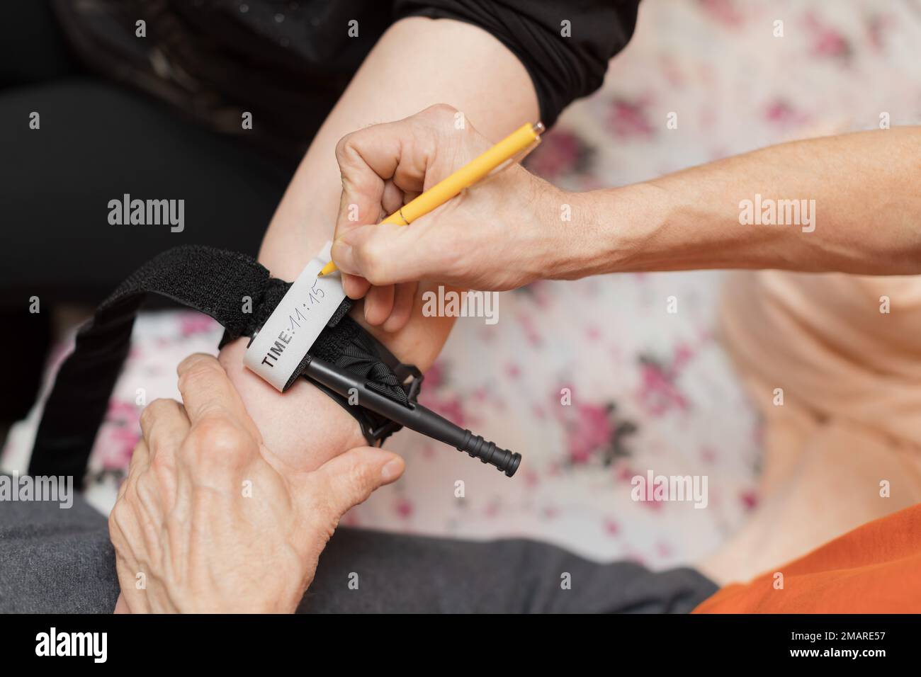 Writing a time on applied tourniquet caucasian older man Stock Photo