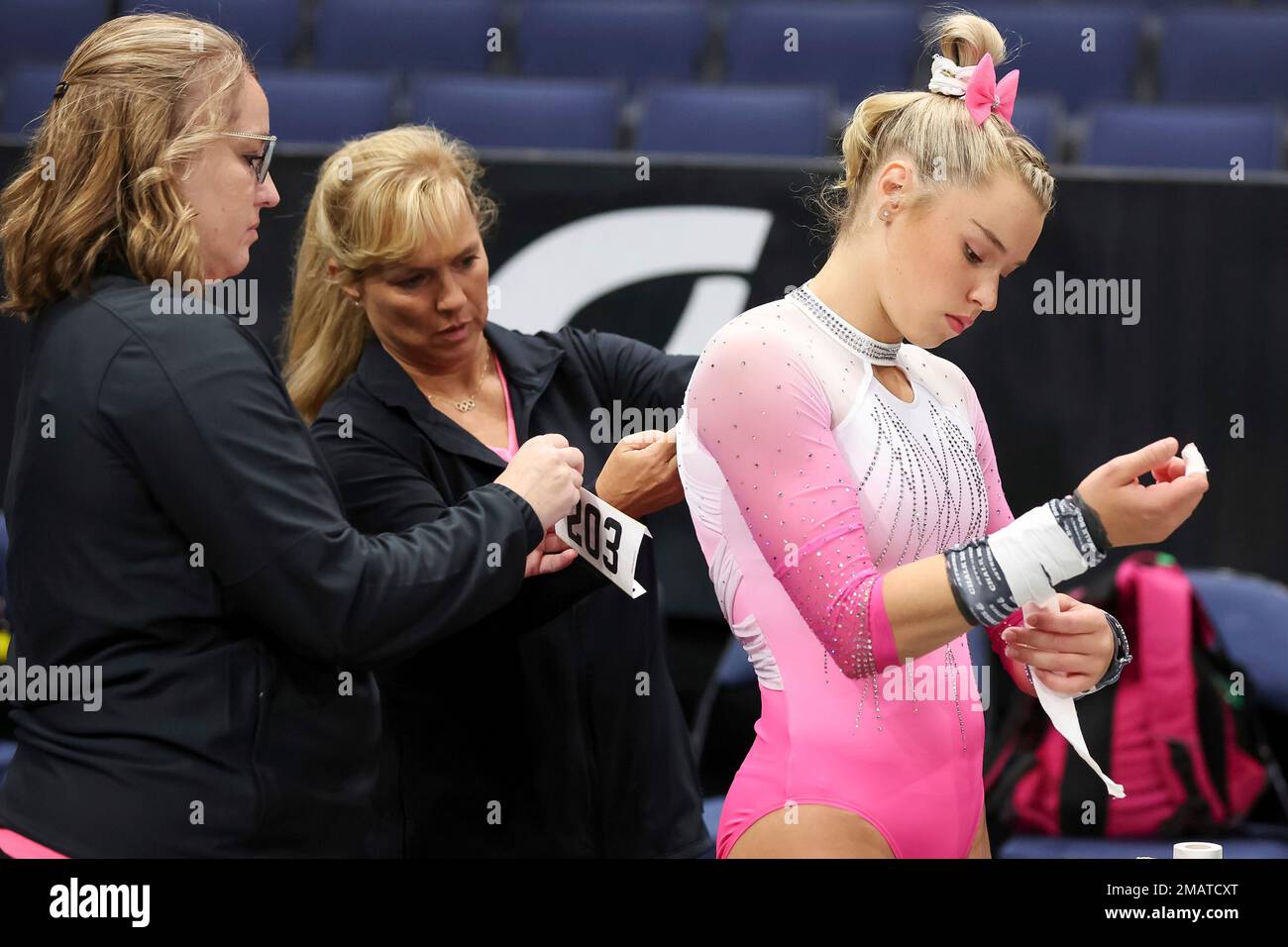 Charlotte Booth tapes her wrist as her coaches put on her number during