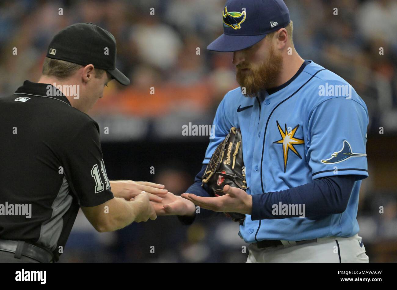 Umpire Junior Valentine, left, inspects the hands of Tampa Bay Rays