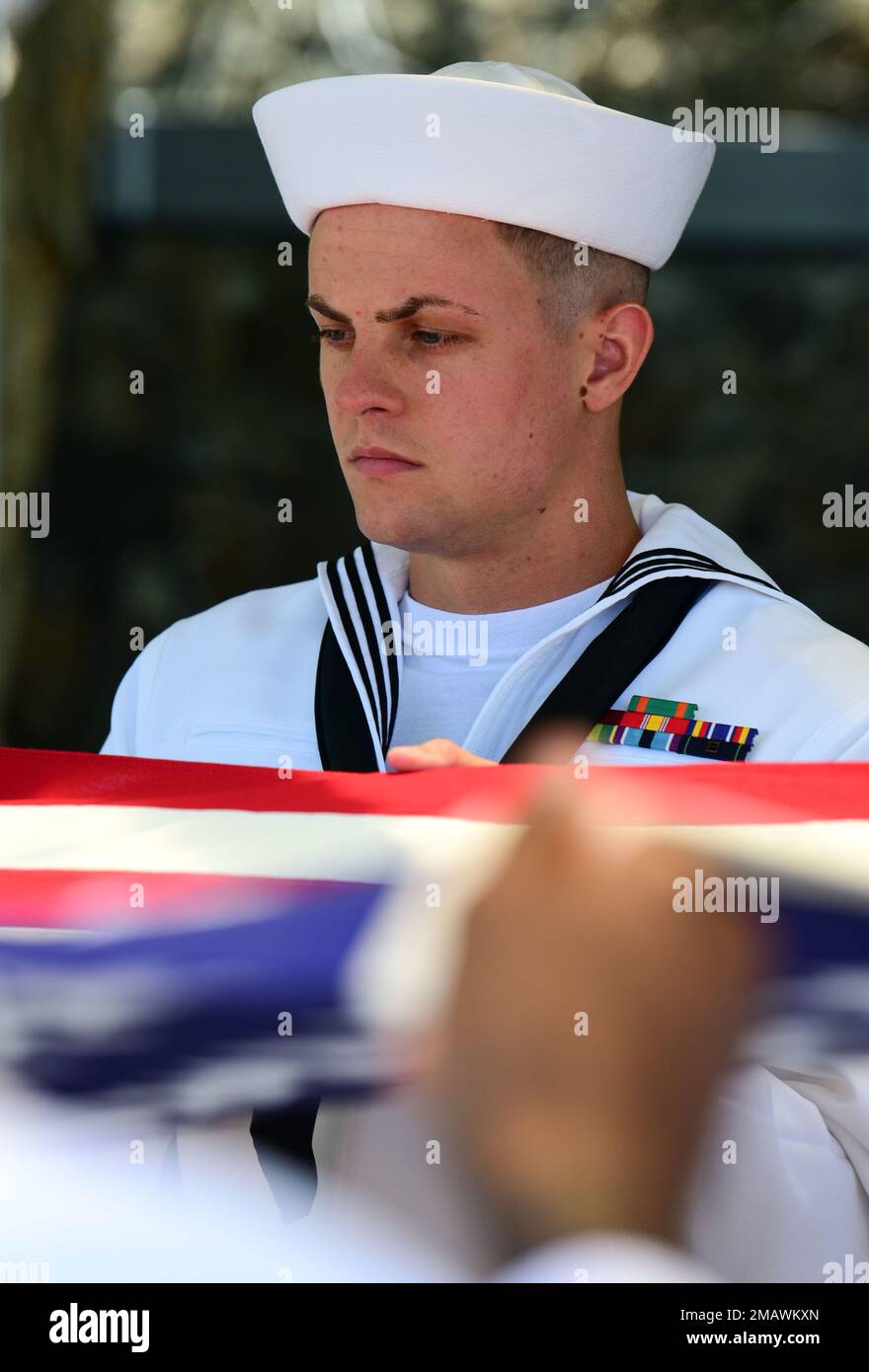 The Navy Region Hawaii Honor Guard spread the American flag over a casket during an internment ceremony for U.S. Navy Fire Controlman 2nd Class George Gilbert, 20, of Indianapolis, at the National Memorial Cemetery of the Pacific, Honolulu, HI, June 6, 2022. Gilbert was assigned to the USS Oklahoma, which sustained fire from Japanese aircraft and multiple torpedo hits causing the ship to capsize and resulted in the deaths of more than 400 crew members on Dec. 7, 1941, at Ford Island, Pearl Harbor. Gilbert was recently identified through DNA analysis by the Defense POW/MIA Accounting Agency for Stock Photo