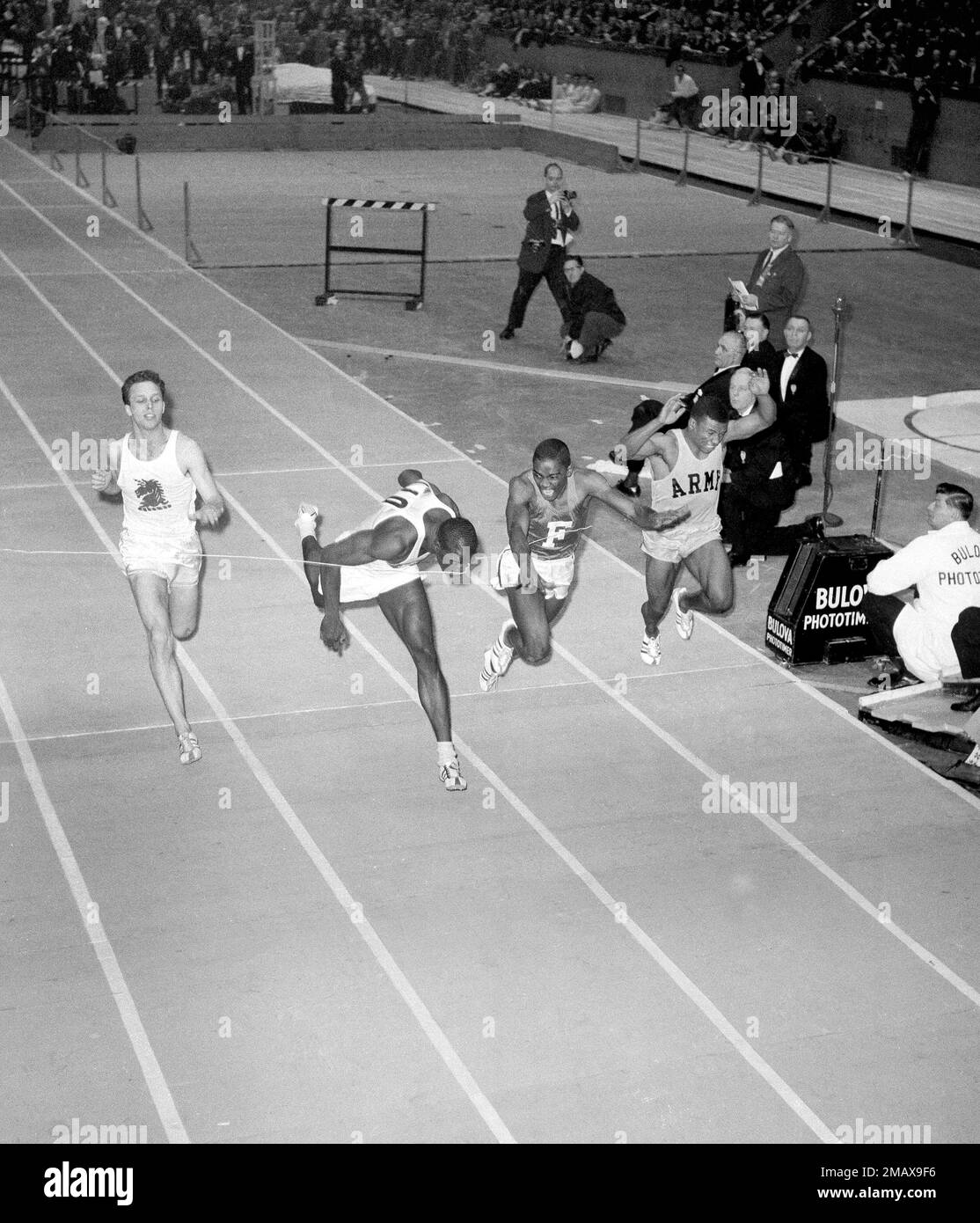 Bob Hayes of Florida A&M, who has equaled the world indoor record for the 60-yard dash, puts his nose to the tape to barely escape an upset in the 60-yard dash at the Millrose Games at Madison Square Garden in New York, Jan. 30, 1964. Hayes' time was 6.1 seconds, equal to the Millrose games record. Sam Perry of Fordham, second from right, led Hayes at the starting blocks, but was nipped at the wire. At left is Gerald Ashworth of Boston A.A. and right is Mel Pender of the U.S. Army. (AP Photo) Stock Photo