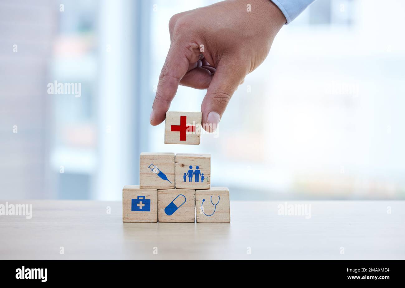Healthcare, insurance and hand with blocks for security, future and investment in family. Surgery, pharmacy and doctor building a hospital foundation Stock Photo