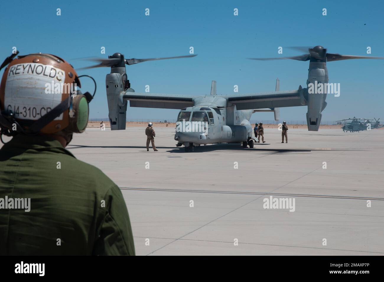U.S. Marine Corps Lance Cpl. Brian Pallares, a tiltrotor mechanic with Marine Medium Tiltrotor Squadron (VMM) 362 (Reinforced), 13th Marine Expeditionary Unit, prepares to guide a MV-22B Osprey during Realistic Urban Training exercise at Marine Corps Air Station Yuma, Arizona, June 7, 2022. The purpose of RUT is to enhance the integration and collective capability of the MEU's command air, ground and logistics elements and prepare the 13th MEU to meet the nation's crisis response needs during its upcoming overseas deployment. Stock Photo