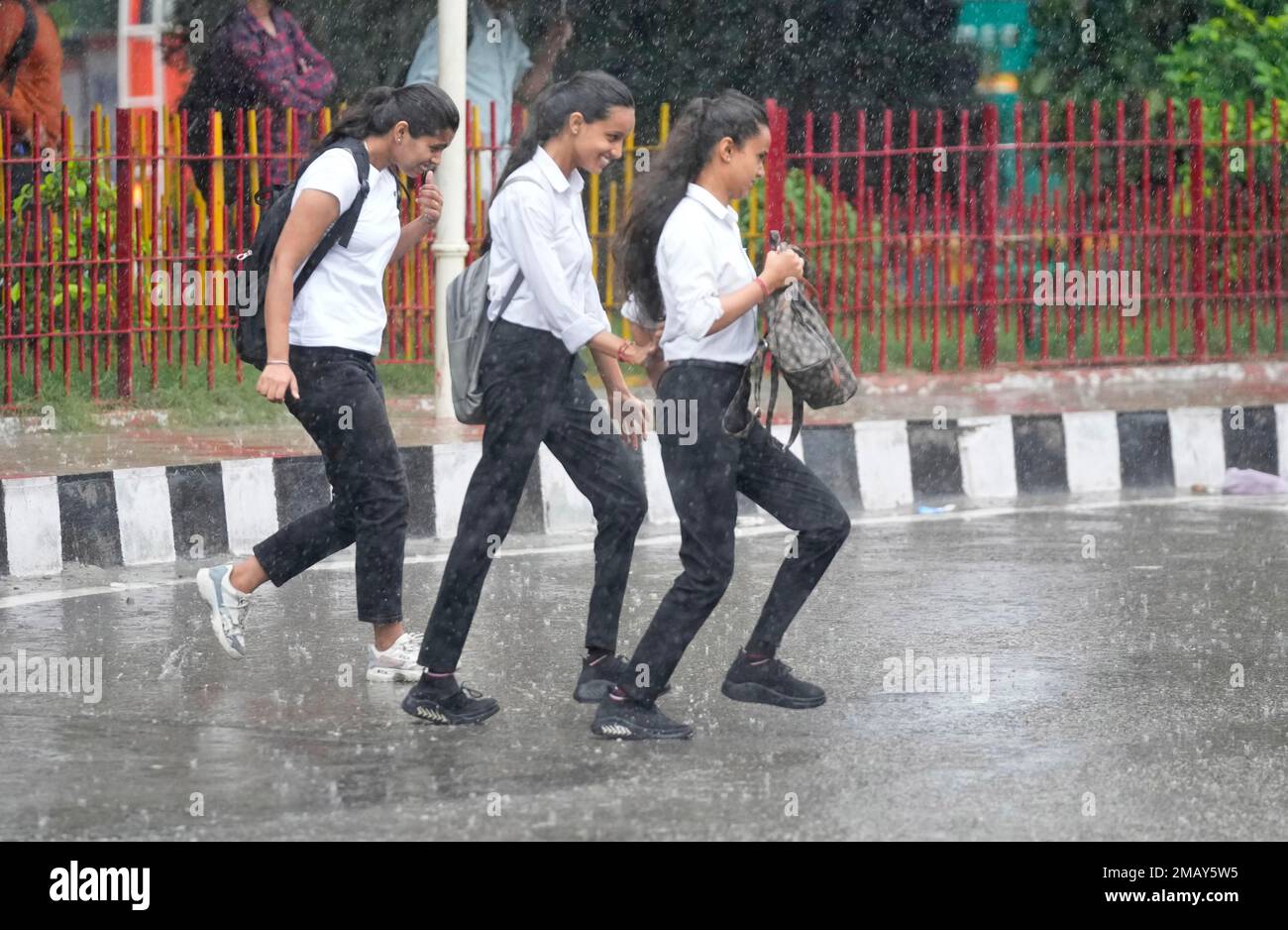 Girls walk in the rain in Jammu, India, Friday, Aug. 5, 2022. The monsoon  rains which usually hit India from June to September are crucial for  farmers whose crops feed hundreds of