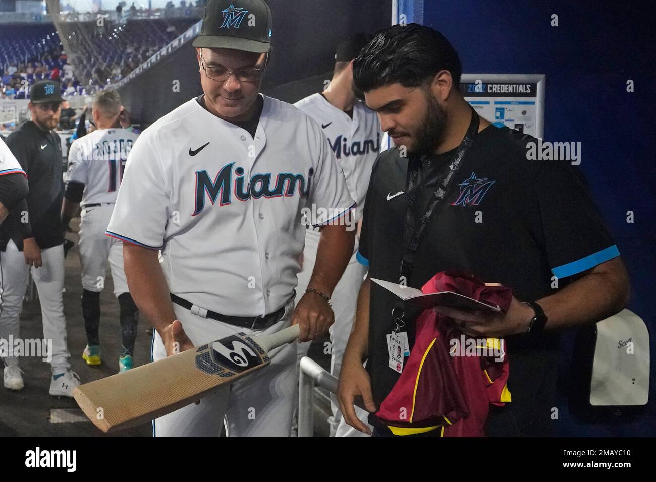 Miami Marlins first base coach Keith Johnson checks out a cricket bat  before the start of a baseball game against the Cincinnati Reds, Wednesday,  Aug. 3, 2022, in Miami. (AP Photo/Wilfredo Lee
