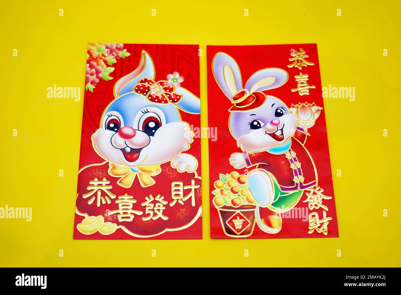 Theme red envelopes with rabbit, Chinese blessing words on yellow background for Chinese Lunar New Year. Hello 2023 year of rabbit. Imlek decoration. Stock Photo