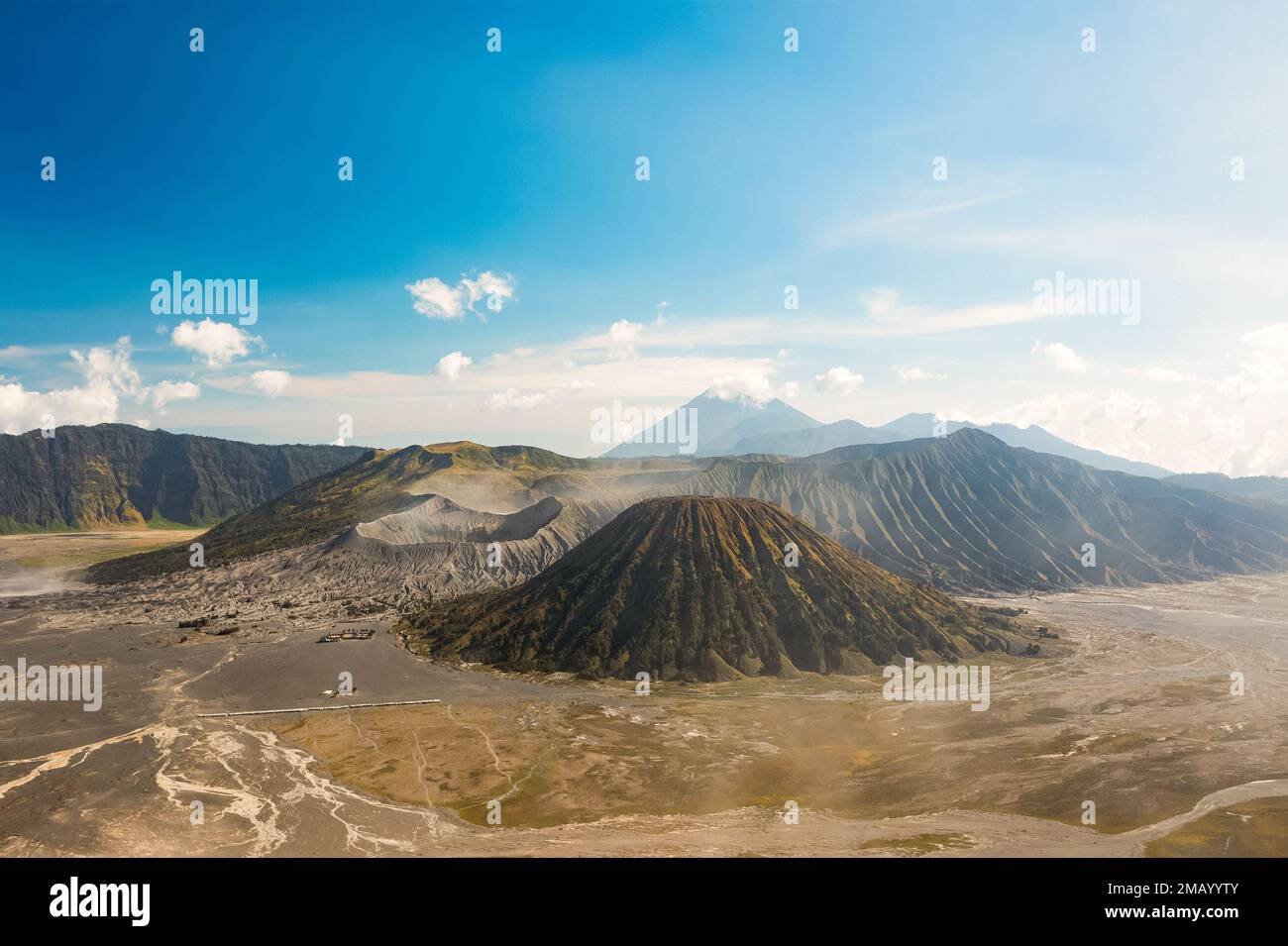 View from above, stunning panoramic view of the Mt Batok, Mt Bromo and the Mt Semeru in the distance during a sunny day. Stock Photo