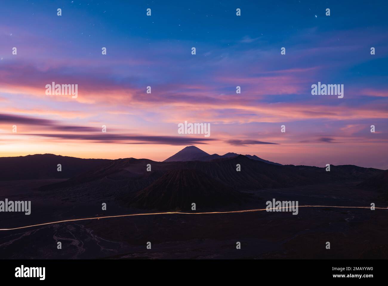 View from above, stunning panoramic view of the Mt Batok, Mt Bromo and the Mt Semeru in the distance illuminated during a dramatic sunrise. Stock Photo