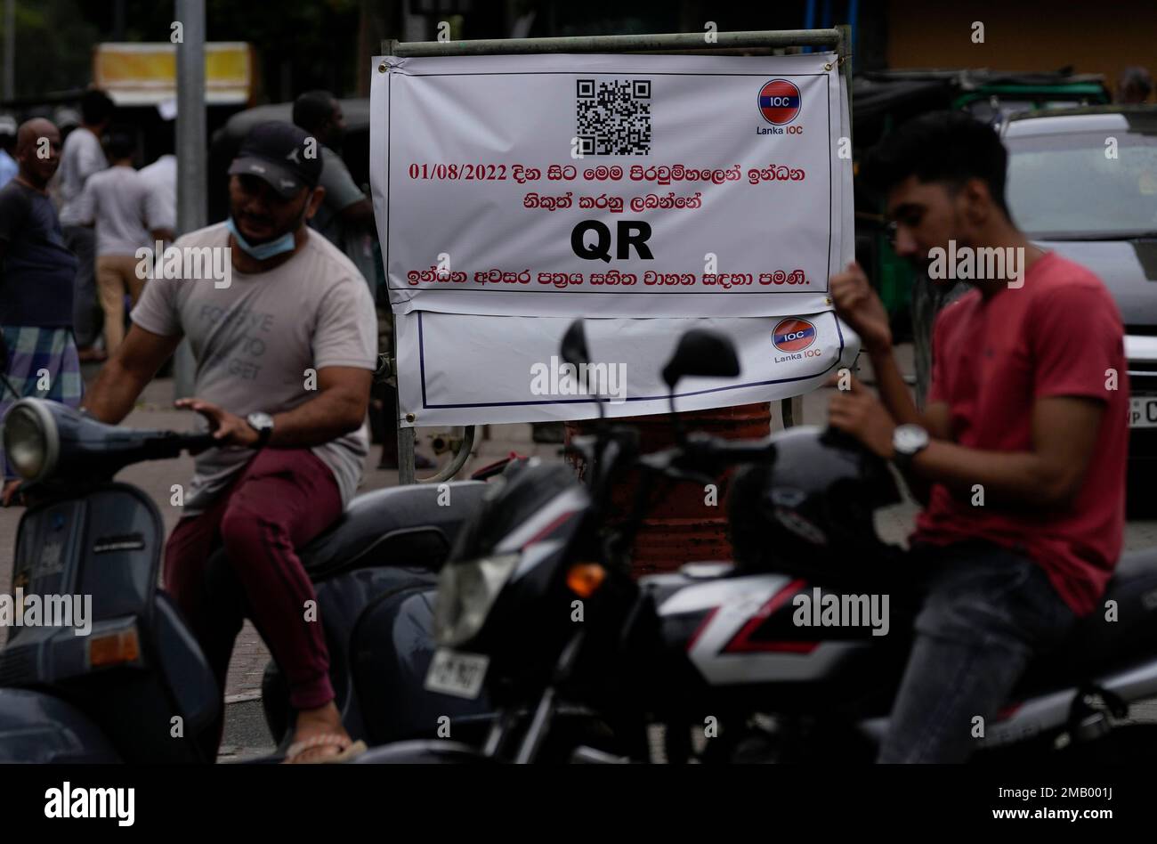 Motorists wait next to a banner that says only those vehicles with QR