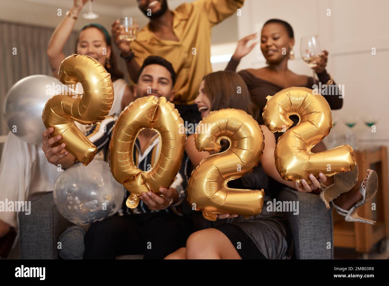 Happy 2022. a diverse group of friends standing together and holding up 2022 balloons during a New Years party. Stock Photo