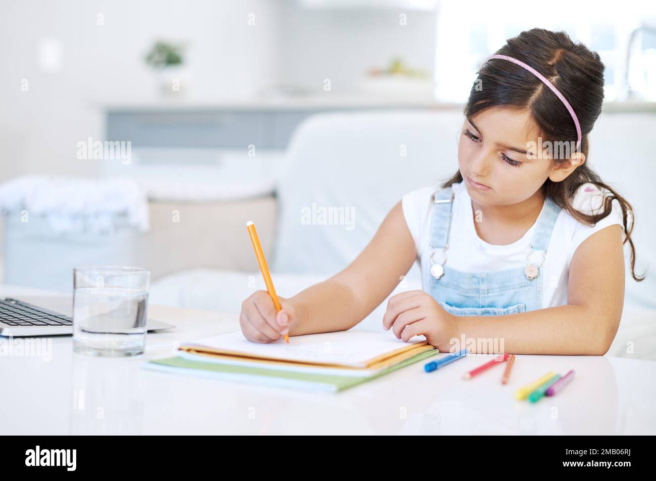 Little girl writing book in classroom Stock Photo